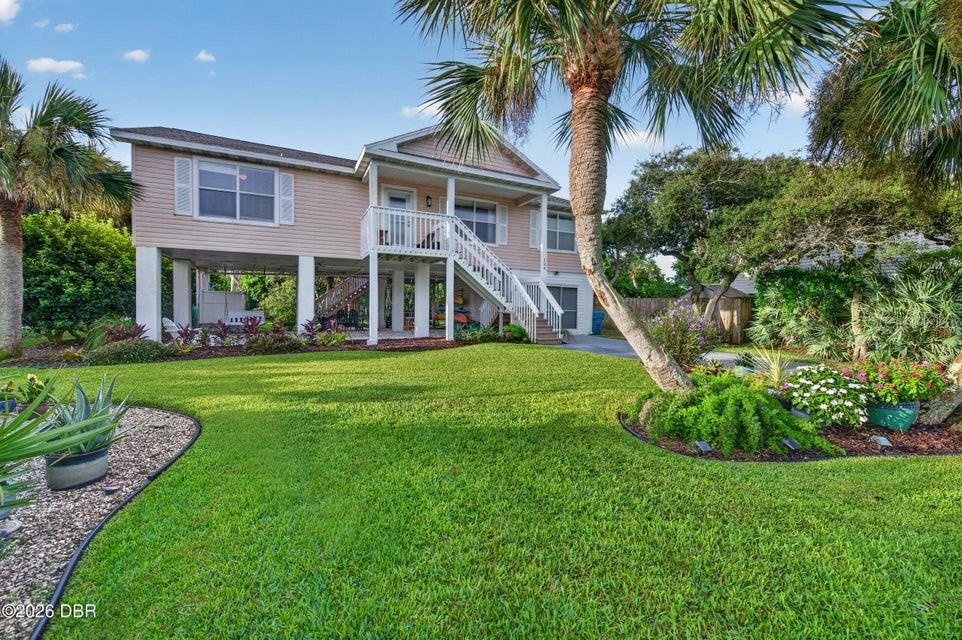 A light-colored elevated house with a front staircase stands above a grassy yard — 124 AVALON DRIVE, ORMOND BEACH, FL
