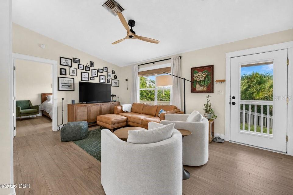 A living room features a tan leather sectional, two white armchairs, and a gallery wall — 124 AVALON DRIVE, ORMOND BEACH, FL