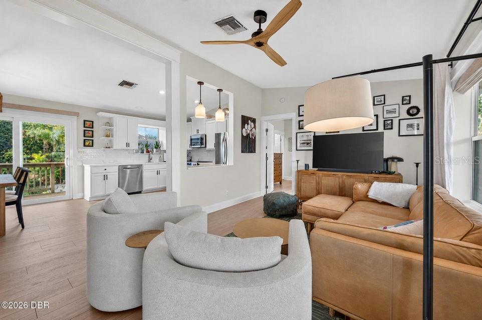 A living room with light wood floors, a leather sectional, and a view into the kitchen — 124 AVALON DRIVE, ORMOND BEACH, FL