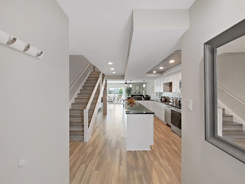 A view from an entryway looking toward a kitchen with an island and a staircase — 433 S PAULA DRIVE UNIT 18, DUNEDIN, FL