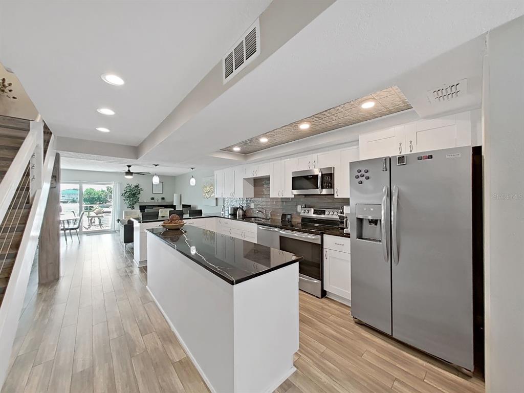 A modern kitchen features white cabinetry, a black countertop island, and stainless steel appliances — 433 S PAULA DRIVE UNIT 18, DUNEDIN, FL