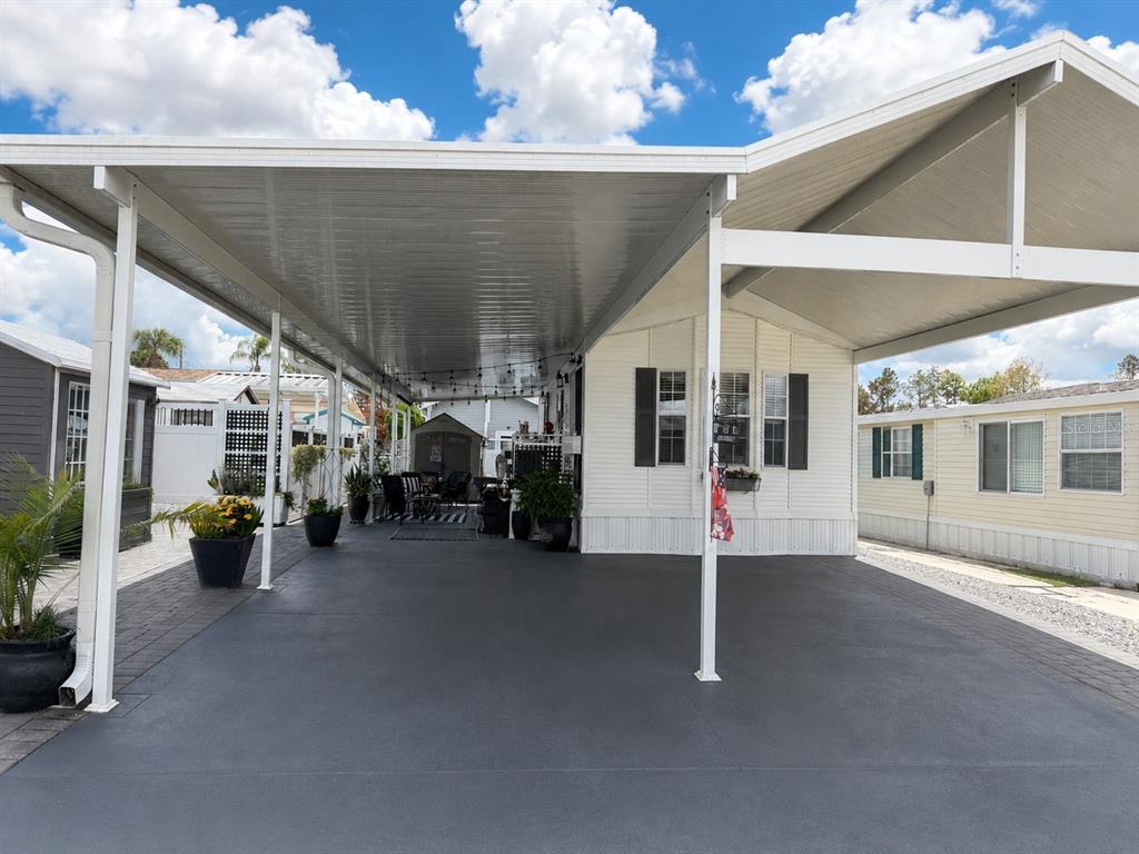 A white mobile home features a large, covered carport with a dark painted concrete floor — 127 TULIP STREET, DAVENPORT, FL