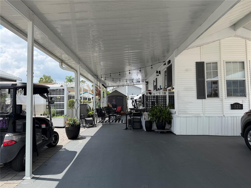 A covered carport area features a concrete floor, string lights, and a golf cart — 127 TULIP STREET, DAVENPORT, FL