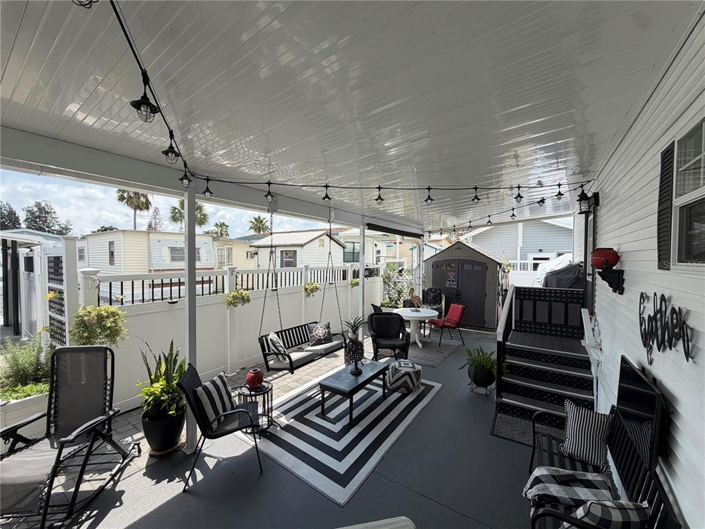 A covered outdoor patio features a striped rug, seating area, and string lights — 127 TULIP STREET, DAVENPORT, FL
