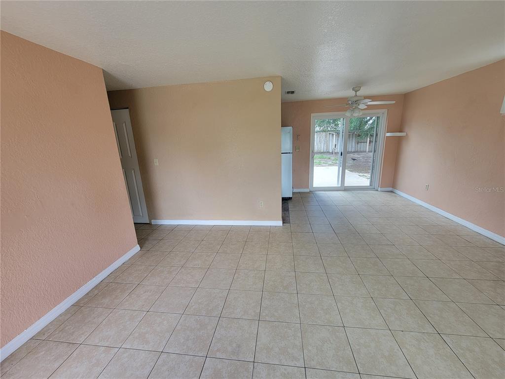 An open-concept living area features peach-colored walls, beige tile flooring, and a sliding glass door — 14297 SW 39TH TERRACE, OCALA, FL