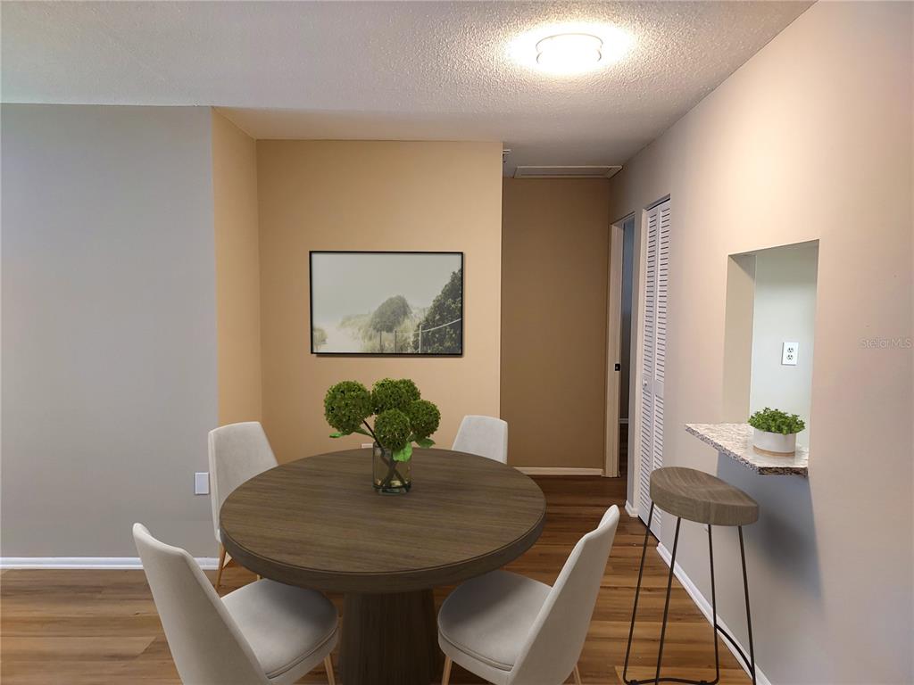 A dining area features a round wooden table, four chairs, and a breakfast bar counter — 6064 ARLENE WAY UNIT 6064, BRADENTON, FL