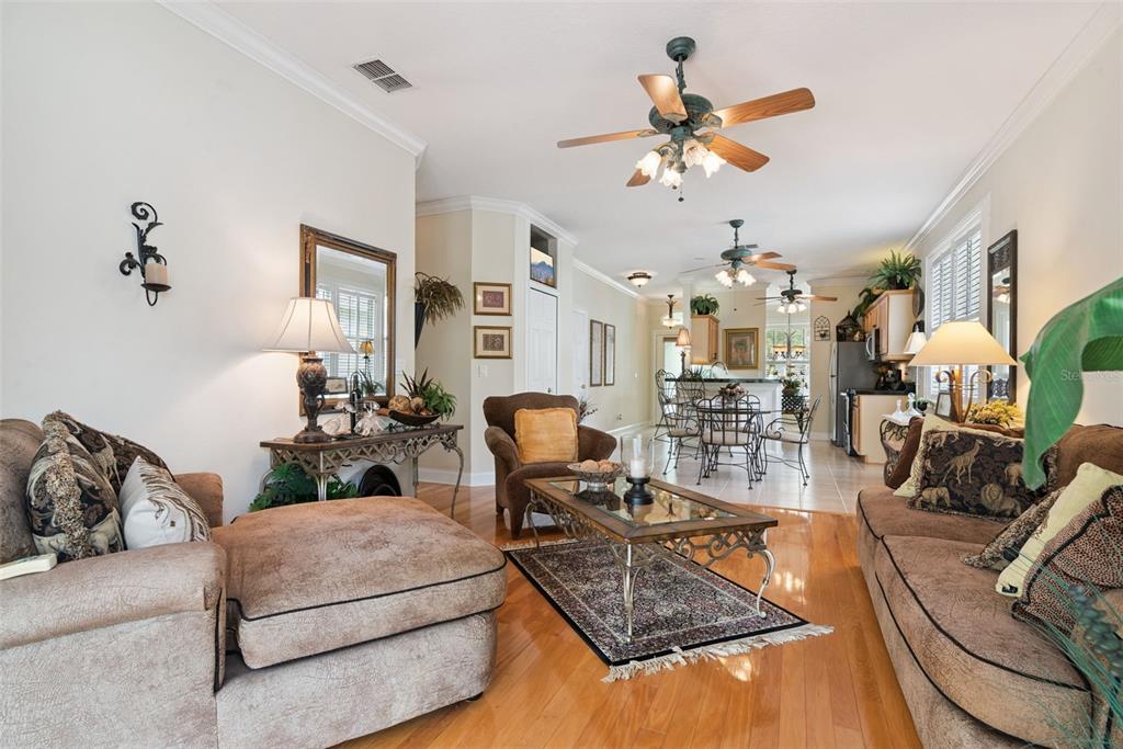 A living room with hardwood floors, a ceiling fan, and an open kitchen in back — 107 PEREGRINE COURT, WINTER SPRINGS, FL