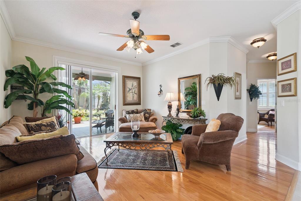 A living room features hardwood floors, a ceiling fan, and sliding glass doors to a patio — 107 PEREGRINE COURT, WINTER SPRINGS, FL