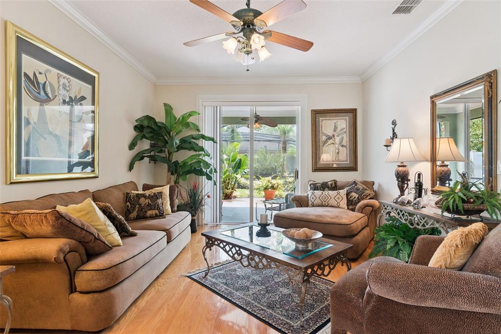 A living room features brown furniture, a glass-top coffee table, hardwood floors, and sliding doors — 107 PEREGRINE COURT, WINTER SPRINGS, FL
