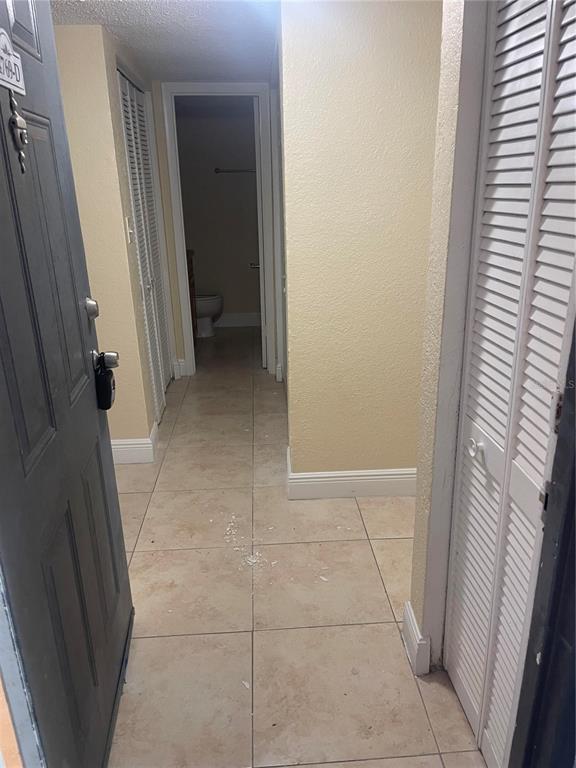 An entryway with tile flooring leads to a hallway with louvered closet doors and a bathroom — 4769 S TEXAS AVENUE UNIT D, ORLANDO, FL
