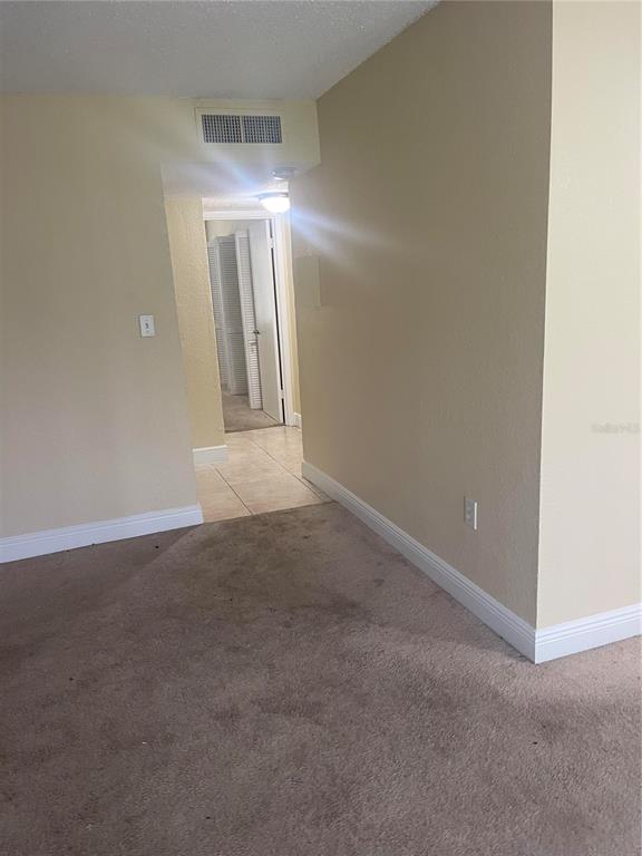 A carpeted room leads through a doorway into a tiled hallway with closet doors — 4769 S TEXAS AVENUE UNIT D, ORLANDO, FL