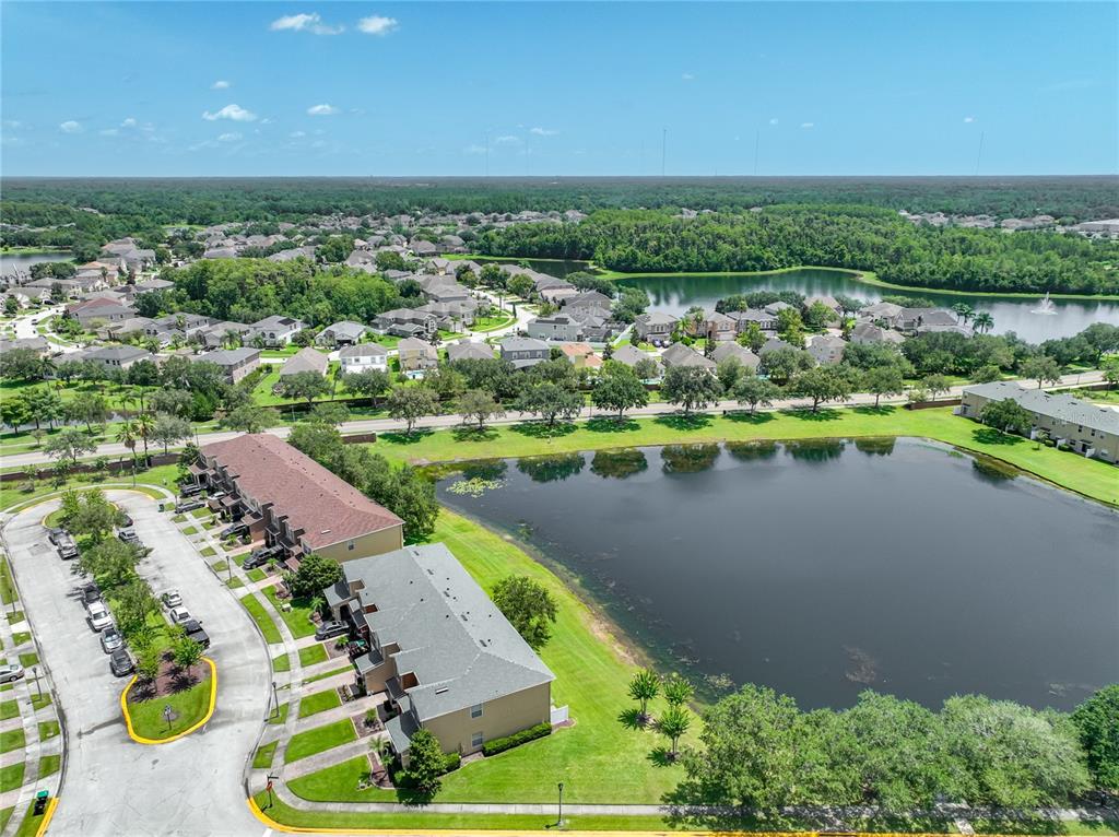 A two-story tan townhouse features a brown garage door, a dark front door, and landscaping — 16543 CEDAR CREST DRIVE, ORLANDO, FL
