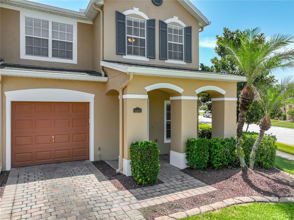 A blue front door and a wicker loveseat sit on a paved front porch — 16543 CEDAR CREST DRIVE, ORLANDO, FL