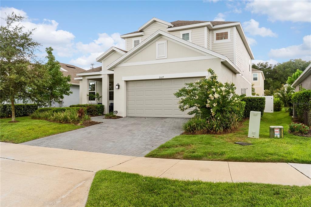 A two-story suburban house with a paved driveway, a garage, and a landscaped front yard — 2527 NATOMA BOULEVARD, MOUNT DORA, FL
