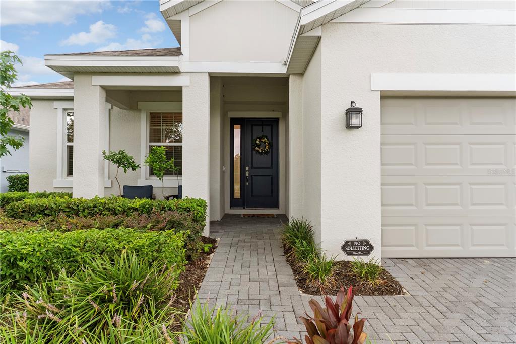 The exterior of a house features a paved walkway, a dark front door, and landscaping — 2527 NATOMA BOULEVARD, MOUNT DORA, FL