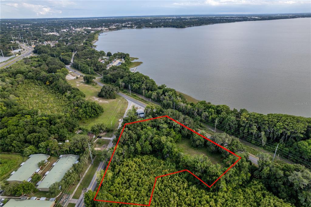 An aerial view shows a wooded, irregularly shaped lot outlined in red near a lake — CR-19A, EUSTIS, FL