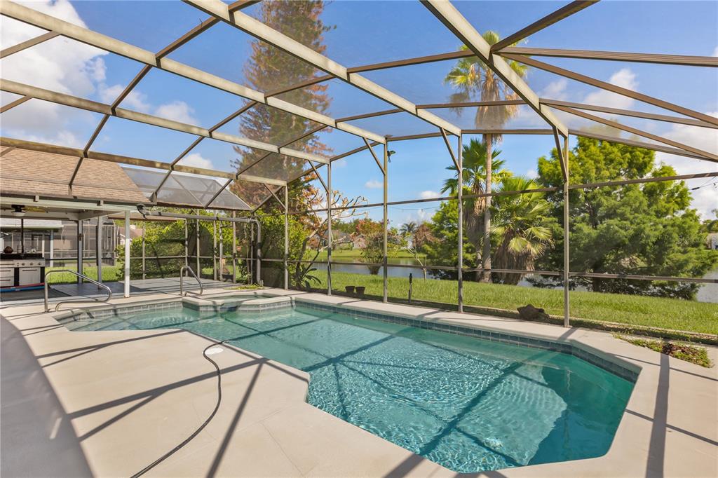 A screened-in swimming pool and spa overlook a grassy yard and a small lake — 3236 TIMUCUA CIRCLE, ORLANDO, FL