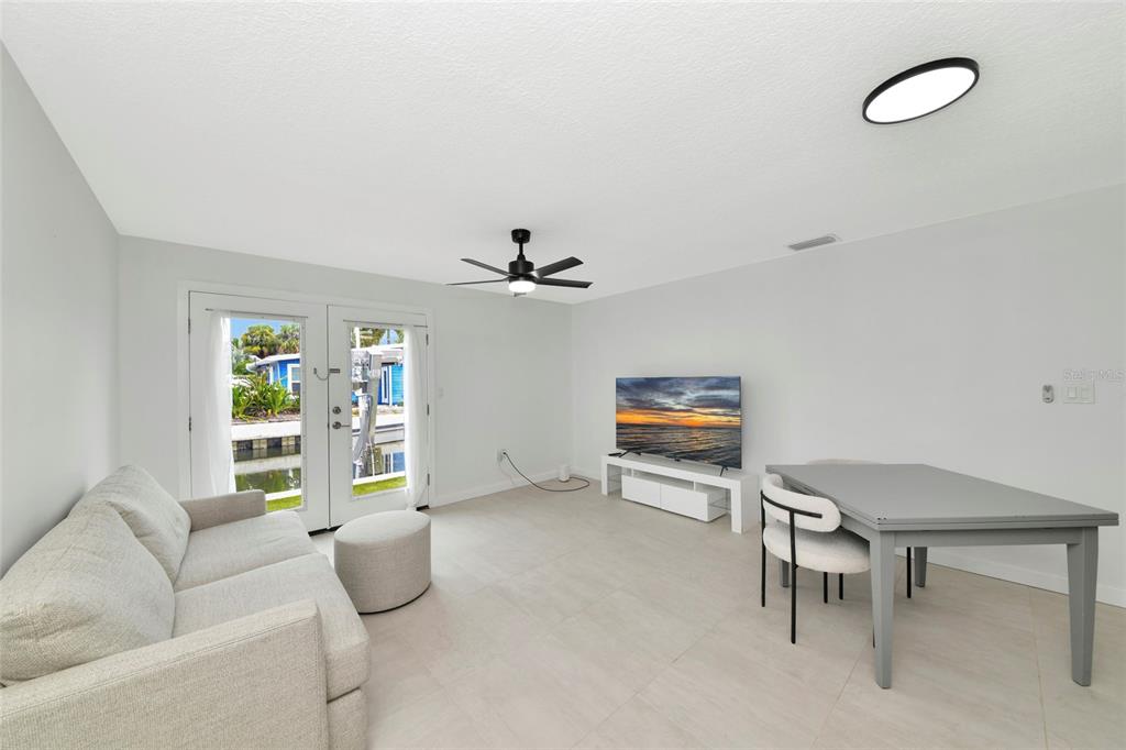 A living and dining area features light tile floors, a ceiling fan, and glass doors — 729 SAINT JUDES DRIVE S UNIT 2, LONGBOAT KEY, FL
