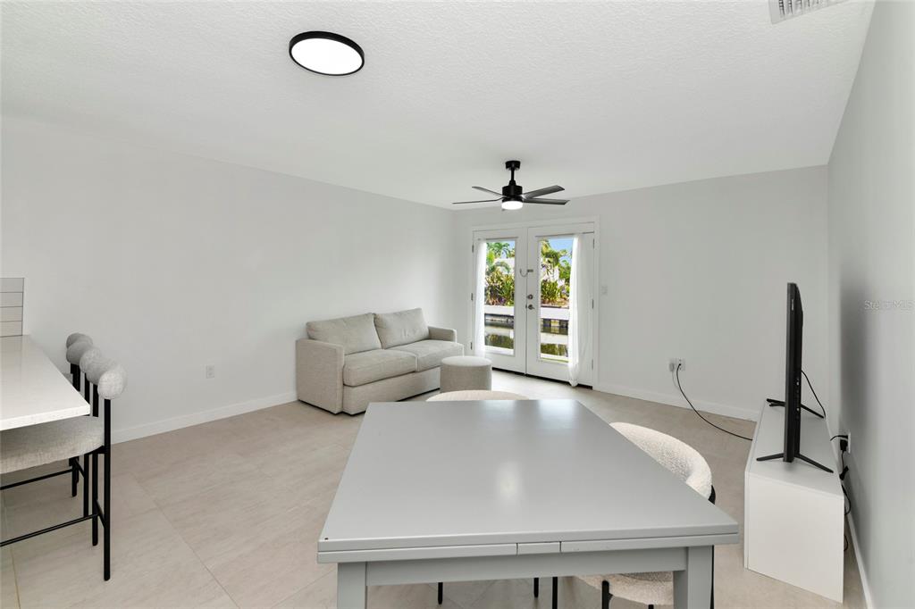 A bright living and dining area features light tile floors, a ceiling fan, and French doors — 729 SAINT JUDES DRIVE S UNIT 2, LONGBOAT KEY, FL