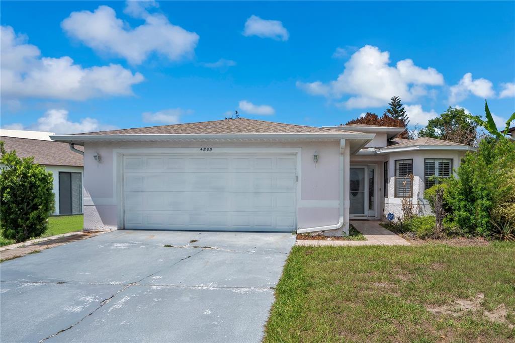 An aerial view shows a single-story house with a light-colored roof and a driveway — 4805 KINGSTON CIR, KISSIMMEE, FL