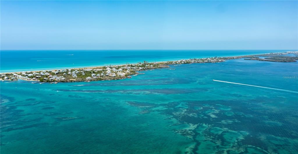 An aerial view shows a narrow island with houses surrounded by turquoise coastal waters — 8864 BAY STREET, PLACIDA, FL