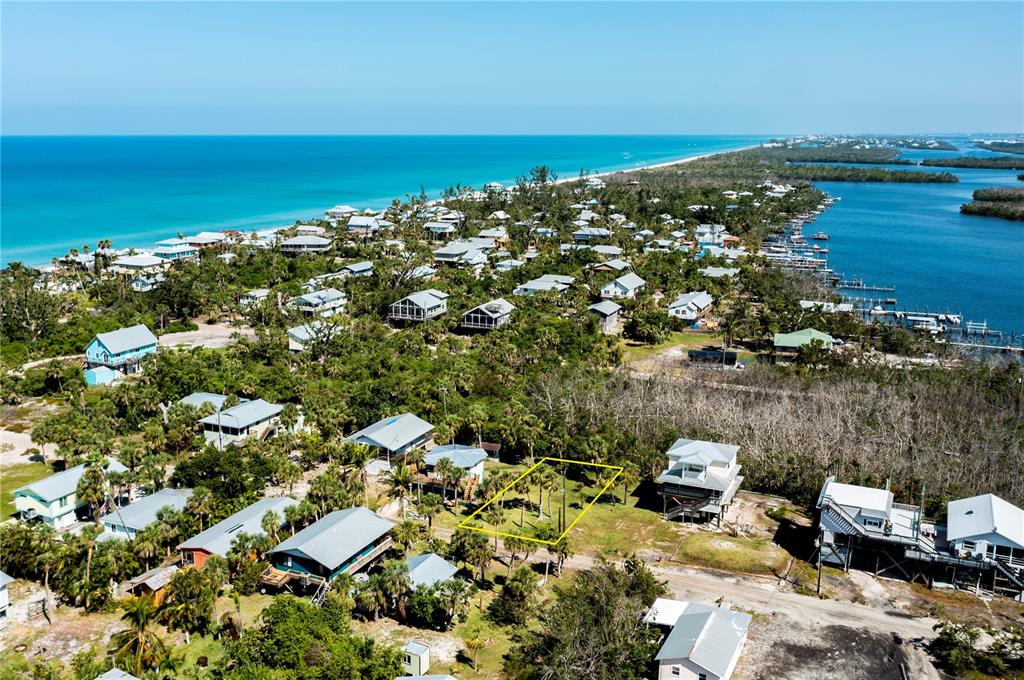 An aerial view shows a vacant, rectangular lot outlined in yellow among coastal houses — 8864 BAY STREET, PLACIDA, FL