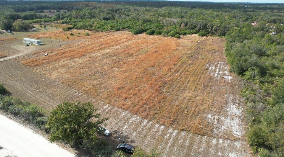 An aerial view shows a large, rectangular, grassy lot bordered by trees and a road — 14421 SEMINOLE TRAIL, WIMAUMA, FL