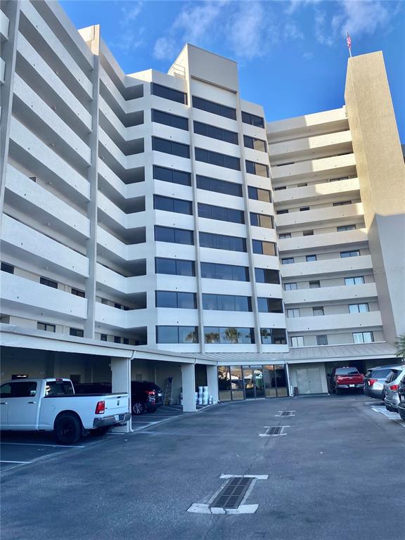 A multi-story apartment building features a covered parking area and a paved lot — 6035 SEA RANCH DRIVE UNIT 901, HUDSON, FL