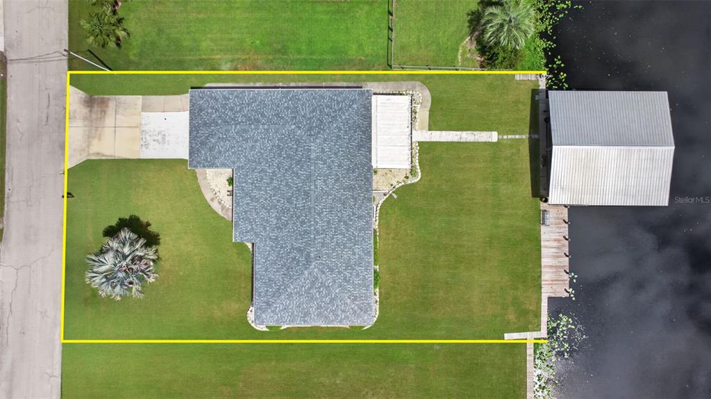 An aerial view shows a house with a gray roof, a driveway, and a boat dock — 1613 JUNO TRAIL, ASTOR, FL