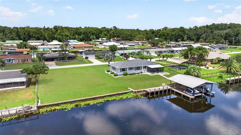 An aerial view shows a waterfront house with a large lawn and a boat dock — 1613 JUNO TRAIL, ASTOR, FL