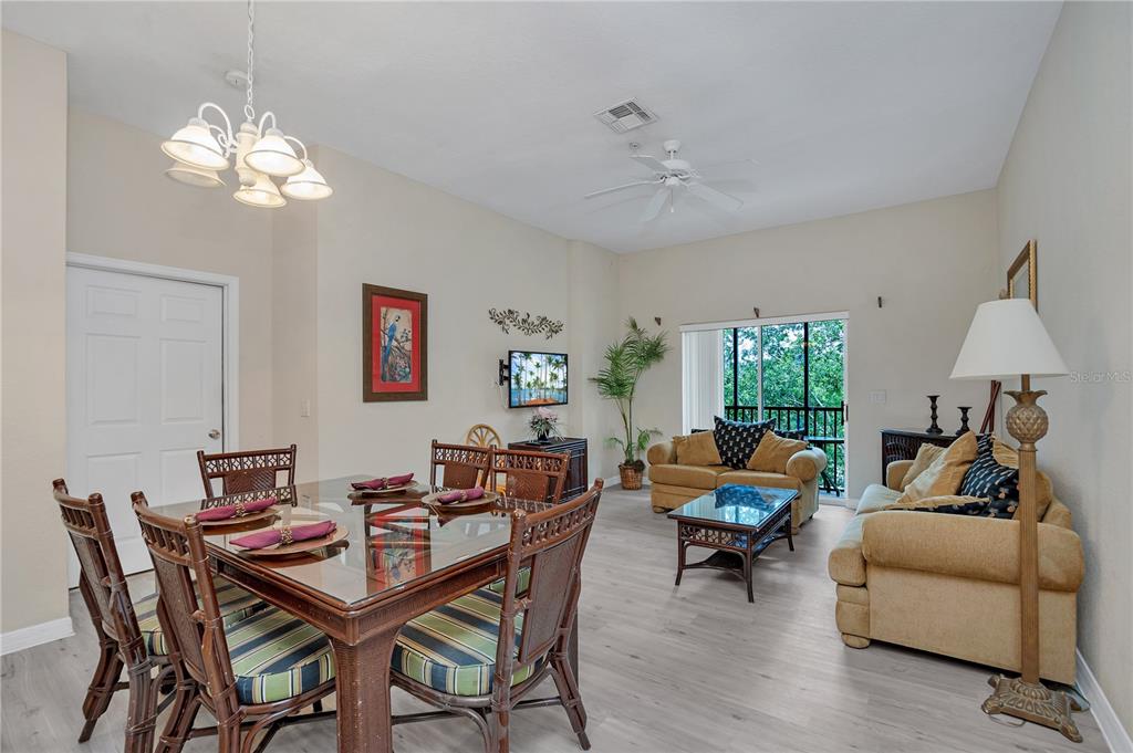An open-concept dining and living area features light wood-look flooring and a glass-topped dining table — 514 LUCAYA LOOP UNIT 514, DAVENPORT, FL