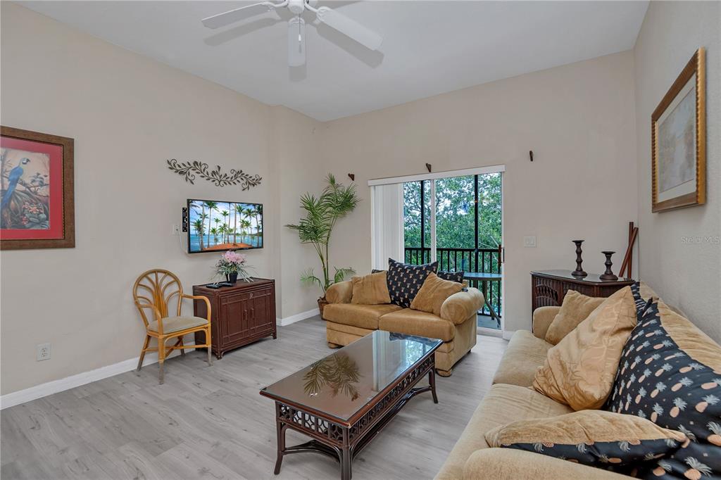 A living room features light wood-look flooring, tan sofas, a coffee table, and a balcony — 514 LUCAYA LOOP UNIT 514, DAVENPORT, FL