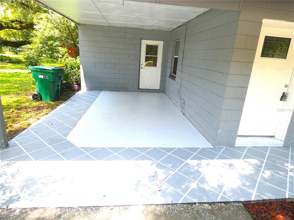 A single-story gray house with a carport sits behind a large tree in a yard — 106 WILLARD AVENUE, FRUITLAND PARK, FL