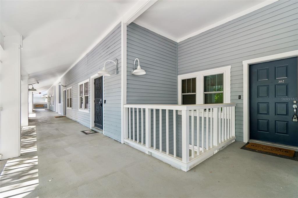 A kitchen with wood cabinets, stainless steel appliances, a tiled backsplash, and light-colored stone flooring — 2599 DOLLY BAY DRIVE UNIT 302, PALM HARBOR, FL