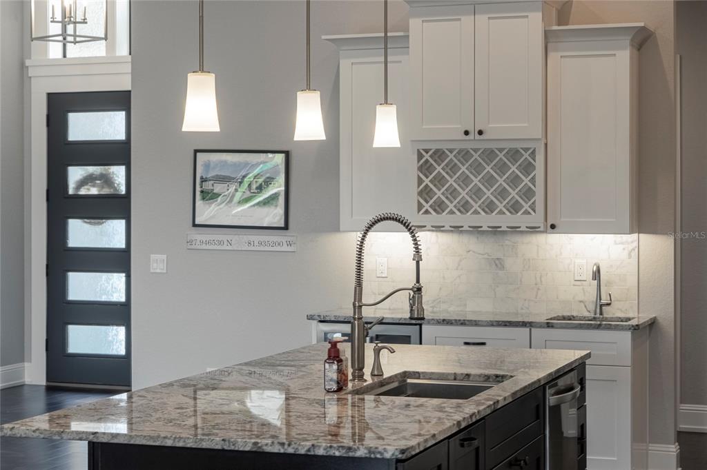 A kitchen features a dark wood island, white cabinetry, stainless steel appliances, and hardwood floors — 6545 EMERALD WOODS LANE, LAKELAND, FL