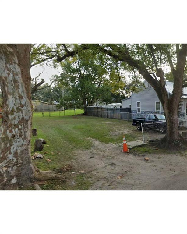A grassy vacant lot sits next to a house with a parked pickup truck — HARDEE STREET, JACKSONVILLE, FL