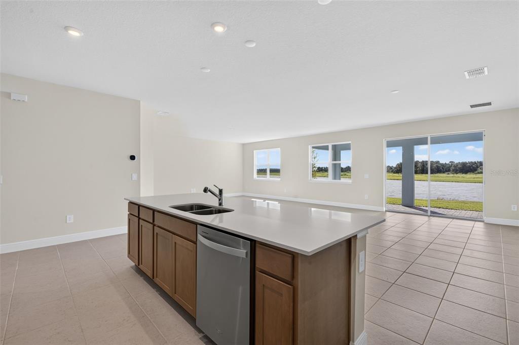 An open-concept kitchen and living area features wood flooring, a center island, and sliding doors — 12907 PIERCE STREET, PARRISH, FL