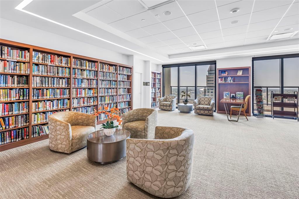 A living room features a red media console, a television, and floor-to-ceiling windows overlooking water — 1 BEACH DRIVE SE UNIT 1907, ST PETERSBURG, FL