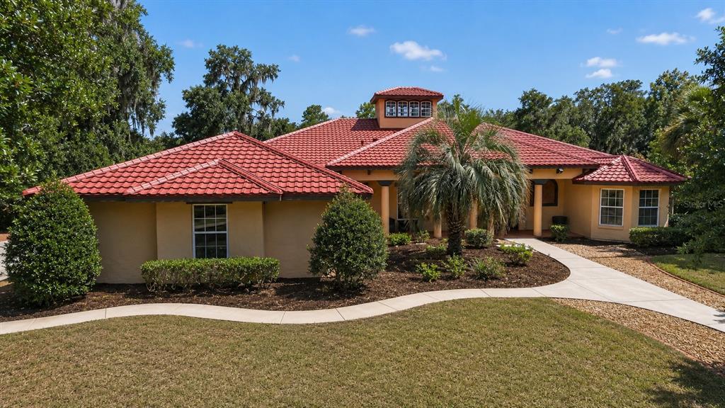 A single-story house with a red tile roof, tan stucco walls, and a palm tree — 11105 W HIGHWAY 326, OCALA, FL