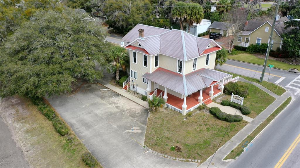 An aerial view shows a two-story yellow house with a metal roof and wrap-around porch — 151 SE 8TH STREET, OCALA, FL