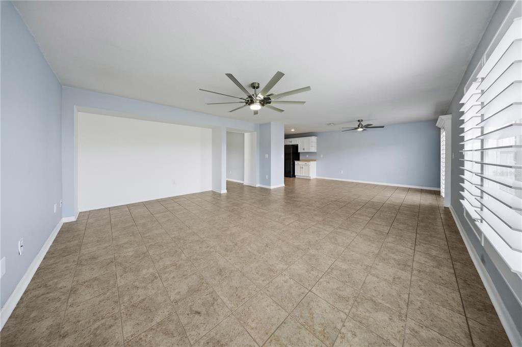 A spacious, open-concept living area features light blue walls, tile flooring, and two ceiling fans — 9515 SIMEON DRIVE, LAND O LAKES, FL