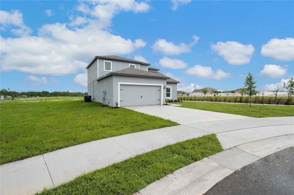 A two-story house with a gray exterior and a two-car garage sits on a corner lot — 624 TANGELO TERRACE, BABSON PARK, FL