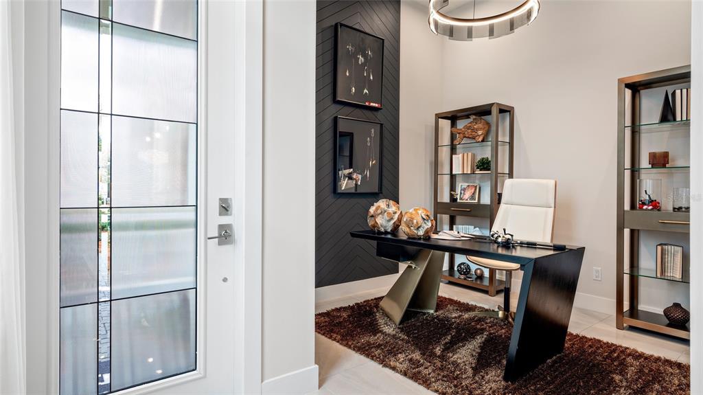 A modern home office features a dark chevron accent wall, glass shelving, and a desk — 1580 BELLAGIO LOOP, TAVARES, FL