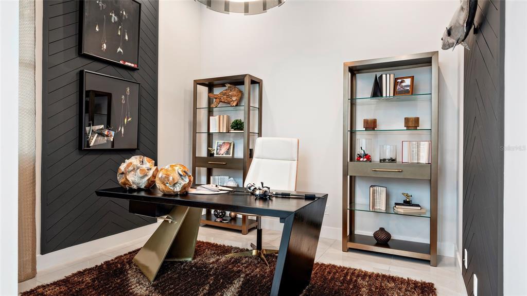 A home office features a dark desk, two glass shelving units, and chevron-patterned accent walls — 1580 BELLAGIO LOOP, TAVARES, FL