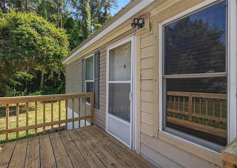 A wooden deck with a railing leads to the front door of a house — 15340 NW 65TH AVENUE ROAD, REDDICK, FL
