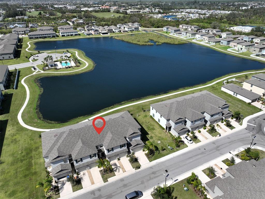 Aerial view of a residential neighborhood featuring townhomes surrounding a large central lake — 928 ROYAL EMPRESS DRIVE, RUSKIN, FL