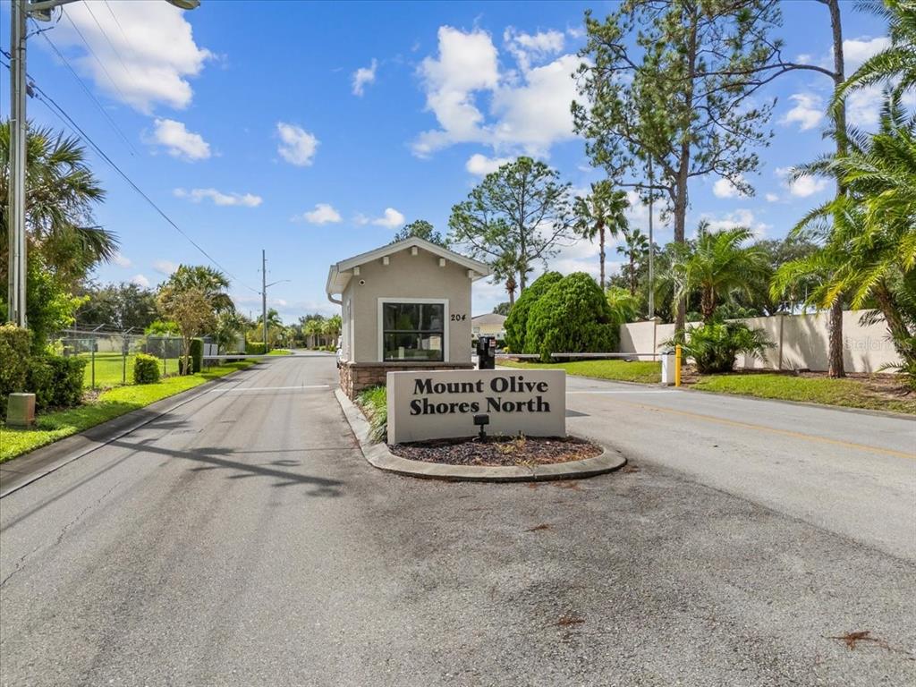 The gated entrance to Mount Olive Shores North features a guardhouse and a paved road — 110 LAYNEWADE ROAD, POLK CITY, FL