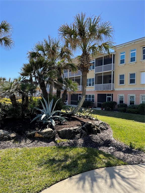 A multi-story building exterior features palm trees, landscaping, and a paved walkway — 3651 S CENTRAL AVE UNIT 312, FLAGLER BEACH, FL