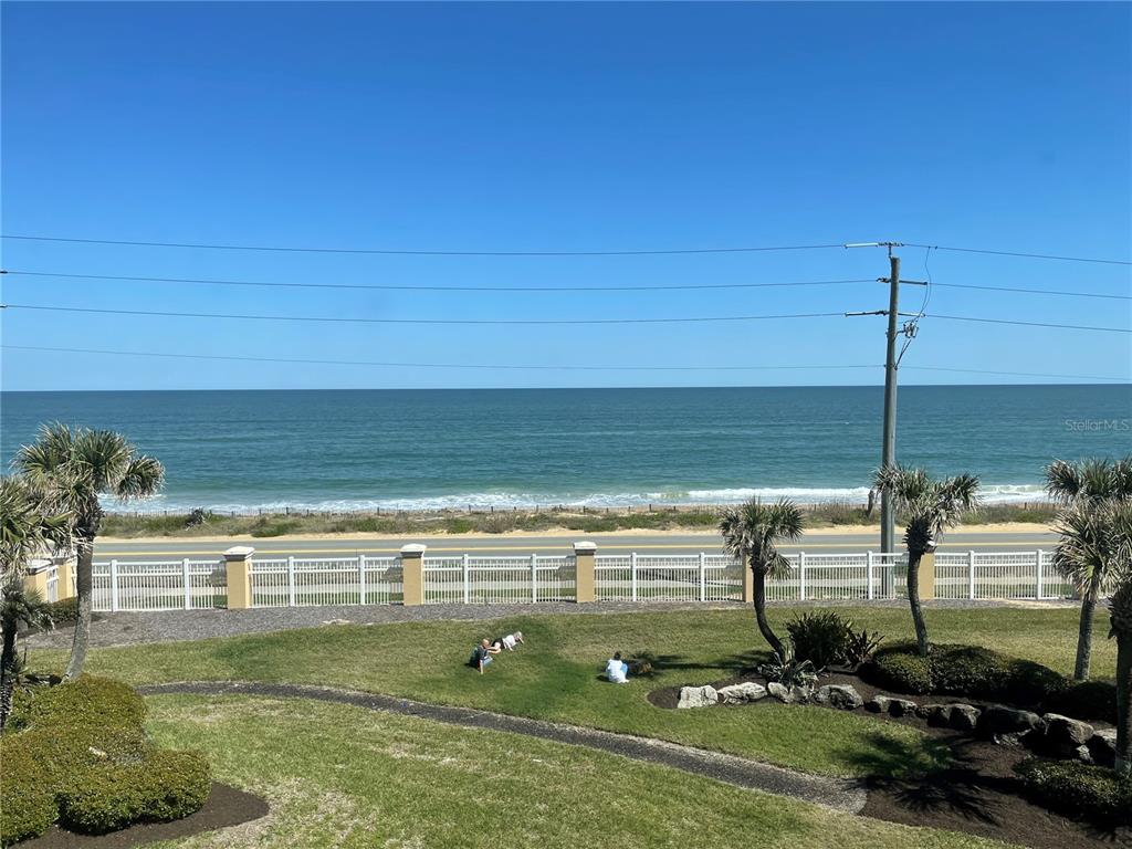 An elevated view of a grassy lawn, a white fence, a road, and the ocean — 3651 S CENTRAL AVE UNIT 312, FLAGLER BEACH, FL