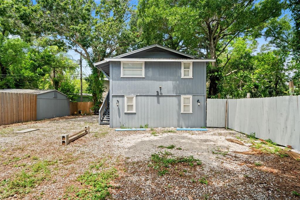 A gray house exterior features a wooden porch, a dark door, and a white-framed window — 4834 TAYLOR STREET N, ST PETERSBURG, FL